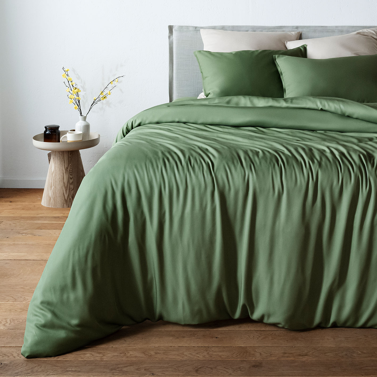 Olive Green bambaw cozy bamboo bedspread on a bed in a bedroom with a side table and decor.