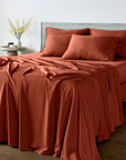Bed with bambaw cozy terracotta bedding set and pillows in a room setting.