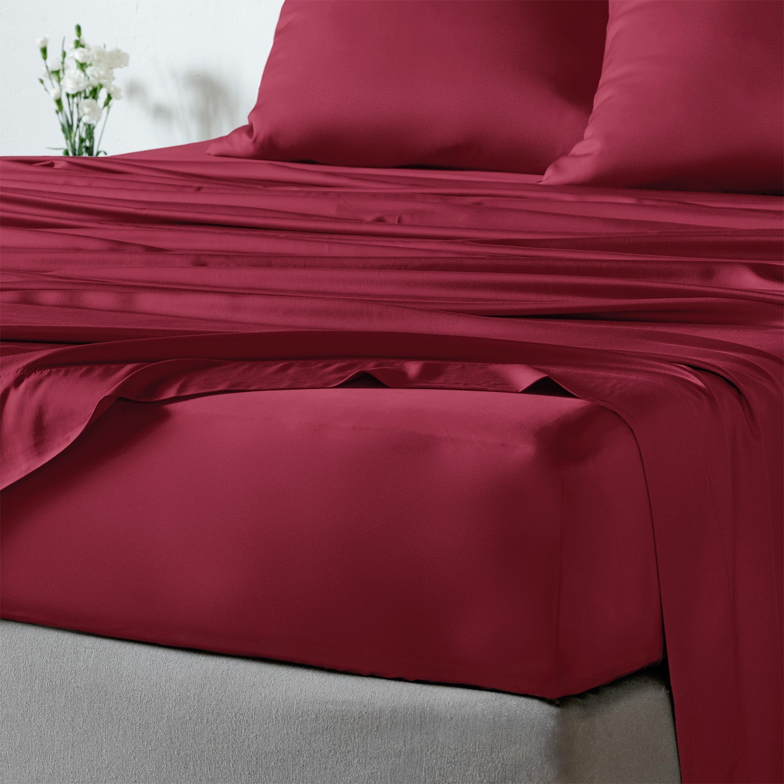 bambaw cozy bamboo bed sheets close up on a bed with fitted sheets and pillows in burgundy red colour