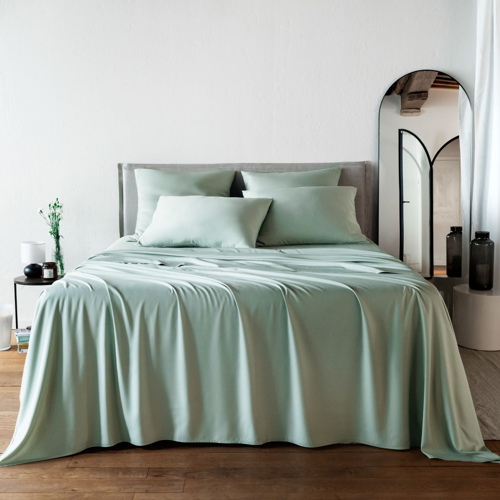 Bambaw Cozy bamboo flat sheet, fitted sheet and pillowcases in sea glass light green colour on a bed in a bright room