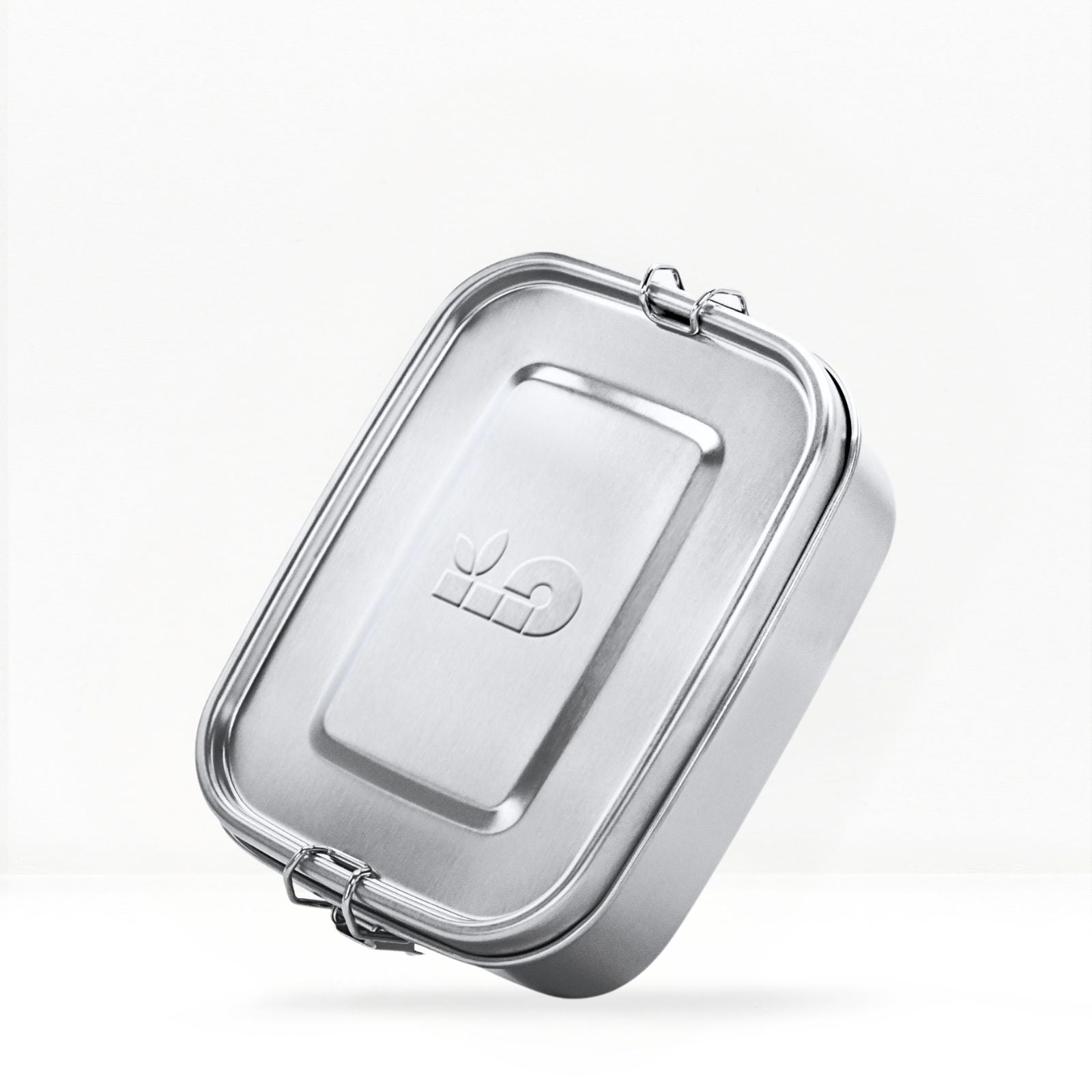 Stainless steel lunch box with its clasp and a tall metal bottle visible behind on a light background
