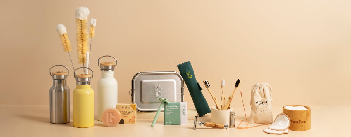 Collection of bambaw reusable products including bottles, containers, and cleaning tools on a beige background