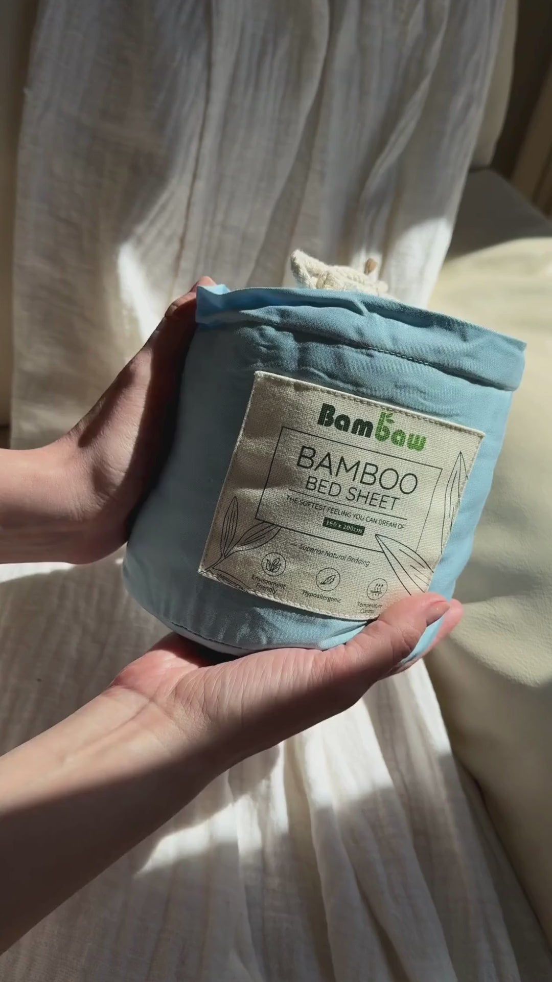 a video of a woman unpacking light blue bambaw cozy bamboo bed fitted sheet