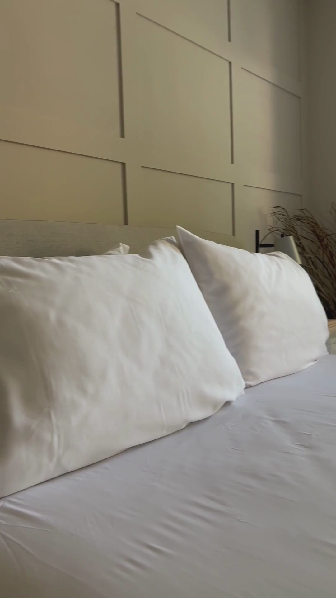 a video of a woman putting on bamboo pillowcases, buttoning bamboo buttons on a bamboo duvet cover and making a bed