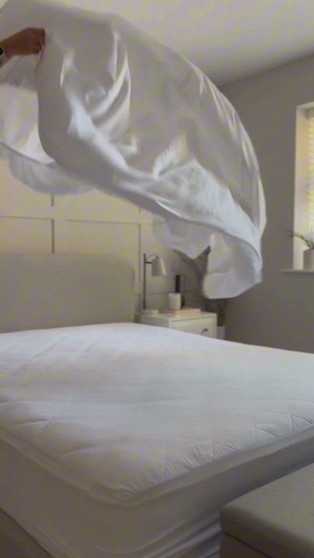 woman making a bed with white bamboo fitted sheet