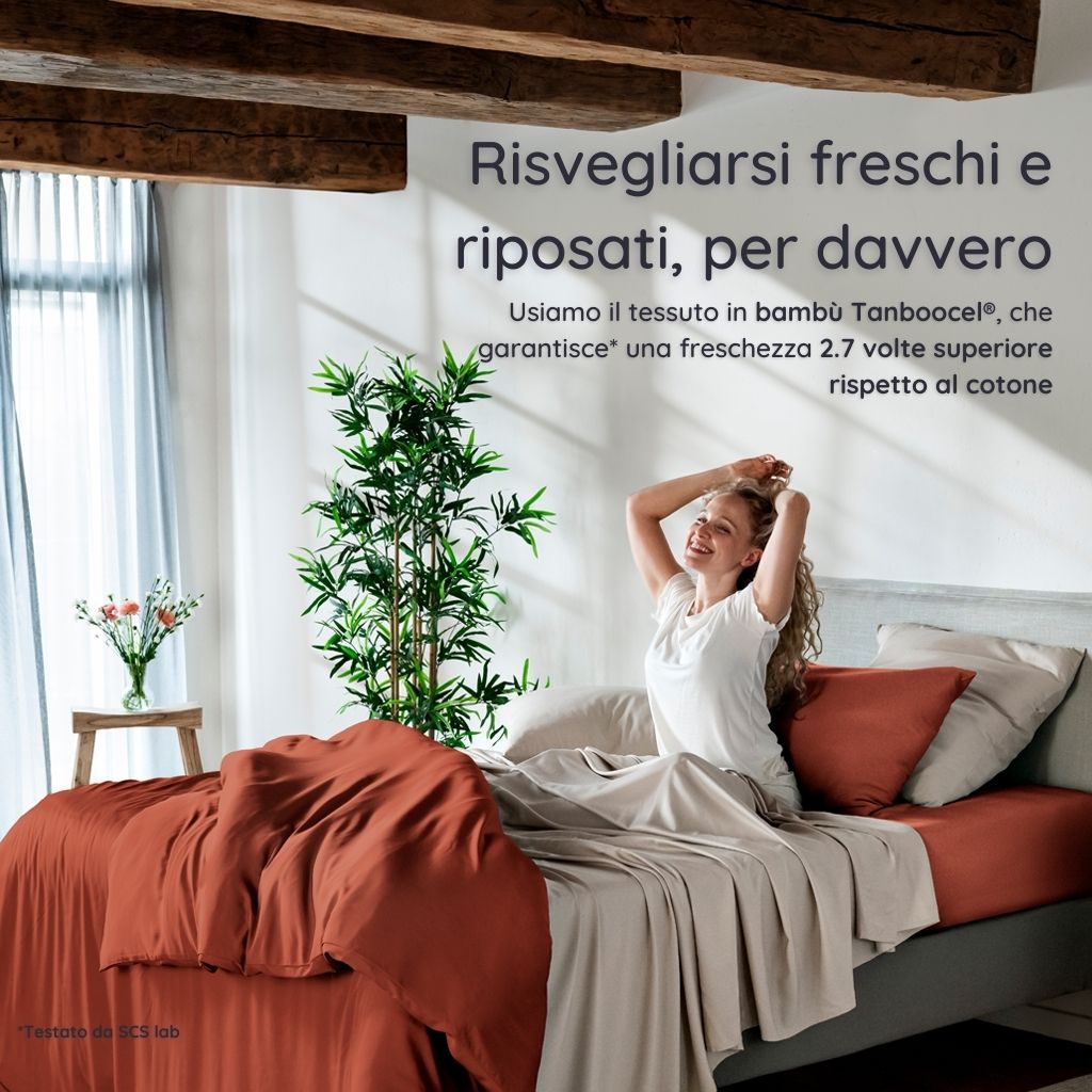 Donna che si sveglia in una camera da letto luminosa con biancheria da letto in bambù terracotta di Bambaw e pareti bianche.